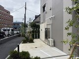エスレジデンス千住大橋ブロード 玄関アプローチから見た建物側面と駐車スペースの様子