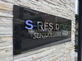 エスレジデンス千住大橋ブロード 石積みの壁面に設置された物件の看板と建物ファサード