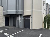 エスレジデンス千住大橋ブロード 駐車スペースから見た建物の外観と駐車場入口