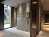 エスレジデンス千住大橋ブロード モダンな共用エントランスホール、グレーのタイル壁と落ち着いた