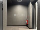エスレジデンス千住大橋ブロード エレベーターホール、グレー系の落ち着いた内装と消火器が設置さ