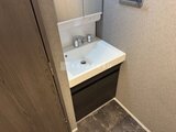 エスレジデンス千住大橋ブロード 白い洗面ボウルと黒い収納がすっきりとまとまった洗面室