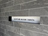 リビオメゾン田端 グレー系タイルで統一されたモダンなエントランスの建物銘板
