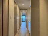 プレディアコート北千住 木目調のドアが並ぶ廊下から開放感のある空間へ続く様子