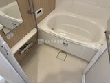 プレディアコート北千住 白いバスタブと木目調のパネル壁が落ち着いた浴室全体の様子