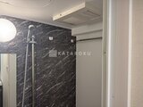 クラリティア上野稲荷町 黒大理石調の壁面とシャワーヘッドが備わるモダンなバスルーム