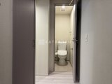 クラリティア上野稲荷町 トイレへの廊下とトイレ室内が見える落ち着いた雰囲気の通路