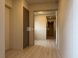 クラリティア上野稲荷町 明るい照明のベージュ系廊下と木目調フローリングの通路