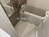 クラリティア上野稲荷町 木調パネルと白いバスタブが配置されたバスルーム