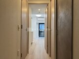クラリティア上野稲荷町 明るい廊下に複数の収納ドアが並び、奥に窓からの光が入る様子
