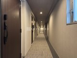 パークアクシス住吉ガーデンスクエア 落ち着いた色合いの廊下に複数の住戸扉が並ぶ共用部の様子