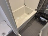 ES-Grande錦糸町ザ・クラス 白い浴槽と暗色の脱衣所床が一体の浴室スペース