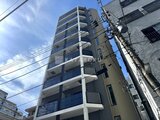 プライムブリス森下スタジオ 青空の下、モダンな白いバルコニーが印象的なマンション外観