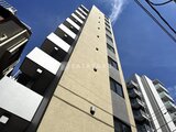 プライムブリス森下スタジオ 下から見上げた建物外観、青空に映える縦長のファサード
