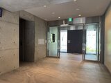 プライムブリス森下スタジオ コンクリート壁と木調床のモダンなエントランスホール