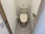 ドゥーエ銀座イースト3 温白色の壁とグレーの床材で統一された清潔感のあるトイレ空間