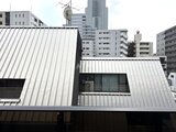 ドゥーエ銀座イースト3 モダンな金属板張りの外観と都市風景が映る建物の屋根面