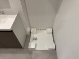 ドゥーエ銀座イースト3 白い洗濯機置き場と洗面台が配置されたコンパクトな洗面脱衣室