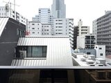 ドゥーエ銀座イースト3 都市景観を背景にした、モダンな金属屋根が特徴の建物外観