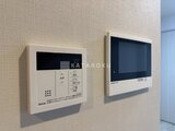 アーバネックス住吉 浅米色の壁に取り付けられた給湯器パネルとモニターホン