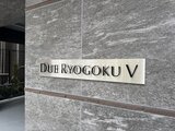 ドゥーエ両国5 グレー系タイルの建物外壁に設置された物件名プレート