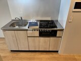 デュオメゾン品川戸越 ガスコンロと調理スペースを備えた木目調のコンパクトキッチン