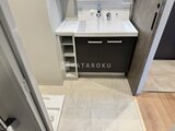 デュオメゾン品川戸越 白系天板と黒扉の洗面台、左側に収納棚を備えた洗面空間