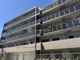 アーバンパーク船堀2 晴天の下、明るいデザインのマンション外観と手前の駐車場の様子