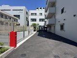 アーバンパーク船堀2 赤い門扉と白い建物に囲まれた明るい駐車場の様子