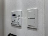 プライムブリス本所吾妻橋 白いタイル壁に設置された給湯器パネルと照明スイッチの様子
