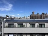 ディームス中野富士見町 屋上から見た建物上部と晴れた空に広がる街並みの風景