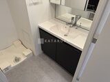 ディームス中野富士見町 モダンな黒の洗面台とトイレが配置された清潔感のある洗面所
