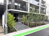 コンフォリア・リヴ文京千駄木 緑化された庭園エリアとエントランスを備えた建物の外観