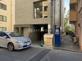 ザ・トリアス錦糸町 駐車場に停まる車と建物エントランスが見える外観の様子