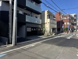 エスレジデンス住吉アクアハト 前面道路から見た建物外観とモダンなガレージ入口の様子