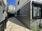 エルファーロ目黒3 庭石張りの通路と落ち着いた外壁が調和した庭の様子
