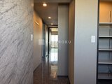 ラグゼナ船堀 大理石風の壁面と収納を備えた、モダンな玄関ホール