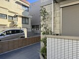 ウェルスクエア幡ヶ谷 駐車スペースとエントランスのある落ち着いた印象の建物外観