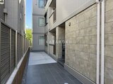 ウェルスクエア幡ヶ谷 建物側面の通路を奥に向けて撮影した風景で、左に機械式駐車場