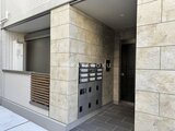 ウェルスクエア幡ヶ谷 石貼りの壁と宅配ボックス付きのエントランス