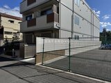 ウェルスクエア幡ヶ谷 門扉から見たモダンな3階建て建物と駐車場の外観