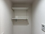 ウェルスクエア幡ヶ谷 洗濯機置き場上部の棚とバーが備わった洗濯スペース