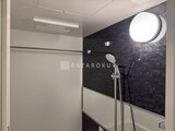 スタイリオ東品川 モダンな配色の浴室、黒いアクセントパネルと白のシャワーヘッド