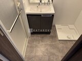スタイリオ東品川 濃色の洗面化粧台と独立した洗い場を備えた洗面脱衣室