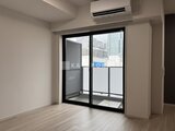スタイリオ東品川 バルコニーへ通じる黒枠ガラス戸から日光が入る明るいリビング