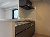 スタイリオ東品川 黒を基調としたシステムキッチンと明るい壁面の開放的なキッチン