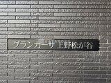 グランカーサ上野松が谷 グレー系タイルが落ち着いた印象の建物外壁と銘板