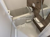 ハイズ三ノ輪2 コンパクトな浴室で、白い浴槽と木目調の壁がまとめられた空間