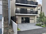 コンフォリア・リヴ駒込西ヶ原 白を基調とした建物のエントランスと駐車スペース
