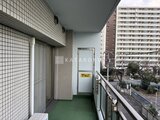 コンフォリア高島平 バルコニーから見た周辺建物と緑色の床材の屋外スペース